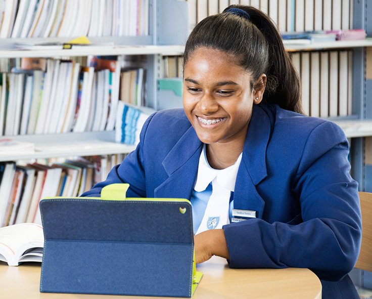 A teenager in at the library in school uniform accessing her school work using Snapplify on a tablet device